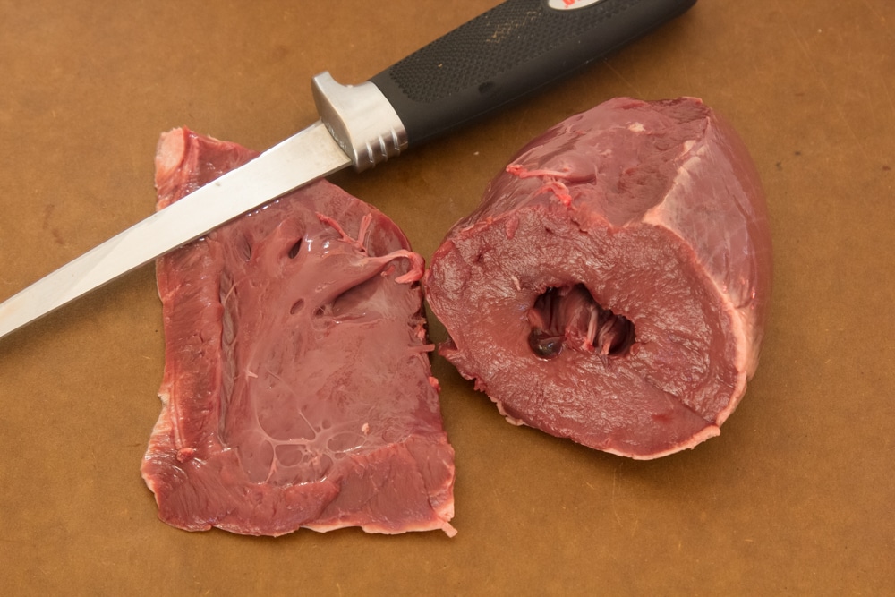 The thinner chamber of the deer heart is removed with a knife - Modern Carnivore